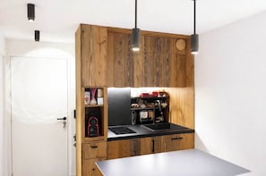 Une cuisine moderne avec des meubles en bois, un plan de travail noir et une cuisinière intégrée.