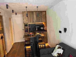 Un espace de vie compact comprenant un coin cuisine, un coin repas et un coin salon.