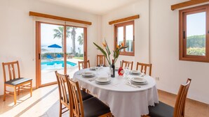 Un coin repas avec une table ronde, des chaises et une vue sur une piscine.