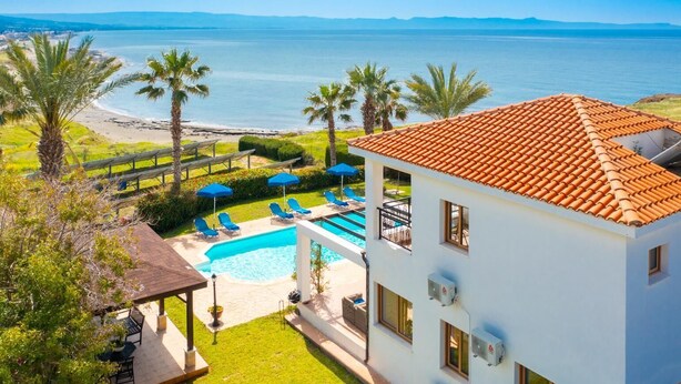 Un complexe hôtelier doté d’une piscine, de chaises longues et offrant une vue sur la mer.