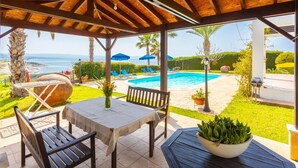 Un espace extérieur abrité comprenant une piscine, des chaises longues et une table agrémentée d’un vase de fleurs.