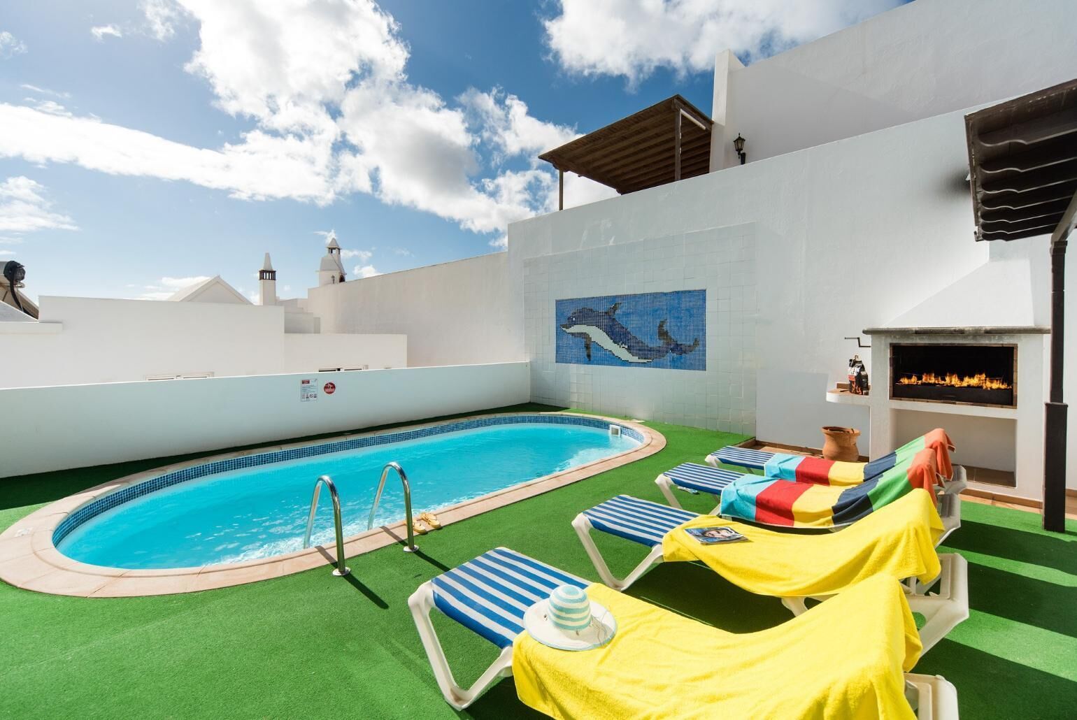 Un espace piscine aménagé sur le toit, avec un plongeoir, des chaises longues et une fresque représentant un dauphin.