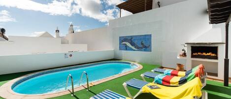 Un espace piscine aménagé sur le toit, avec un plongeoir, des chaises longues et une fresque représentant un dauphin.