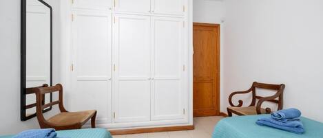 Una habitación con dos camas, un armario de madera, un espejo y una puerta de madera.