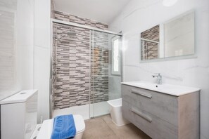A modern bathroom with a glass-enclosed shower, a white sink, and a vanity with drawers. - Villa Reyes - Three Bedroom Villa, Sleeps 6 (Tias)