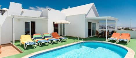 A rooftop pool area with a clear blue pool, multiple lounge chairs, and a view of the cityscape.
