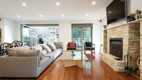 En moderne stue med en sofa, lænestole, et sofabord og en pejs.