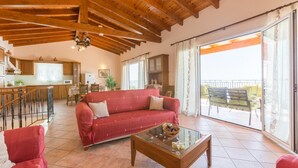 Amplia sala de estar con un sofá rojo, una mesa de centro de vidrio y un balcón con mobiliario exterior.