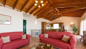 Una sala de estar acogedora con dos sofás rojos, una mesa de centro de cristal y un techo de madera.