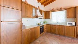 Una cocina con armarios de madera, una estufa, un microondas y una ventana con cortina.