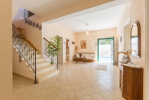 Stairs lead to an upper level, with a console table and framed picture below.