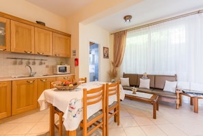 Un espacio habitable compacto con armarios de madera, una mesa de comedor con sillas, un sofá y una mesita de centro.