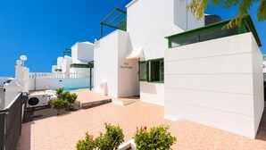 Una villa moderna con piscina, paredes blancas y contraventanas verdes.
