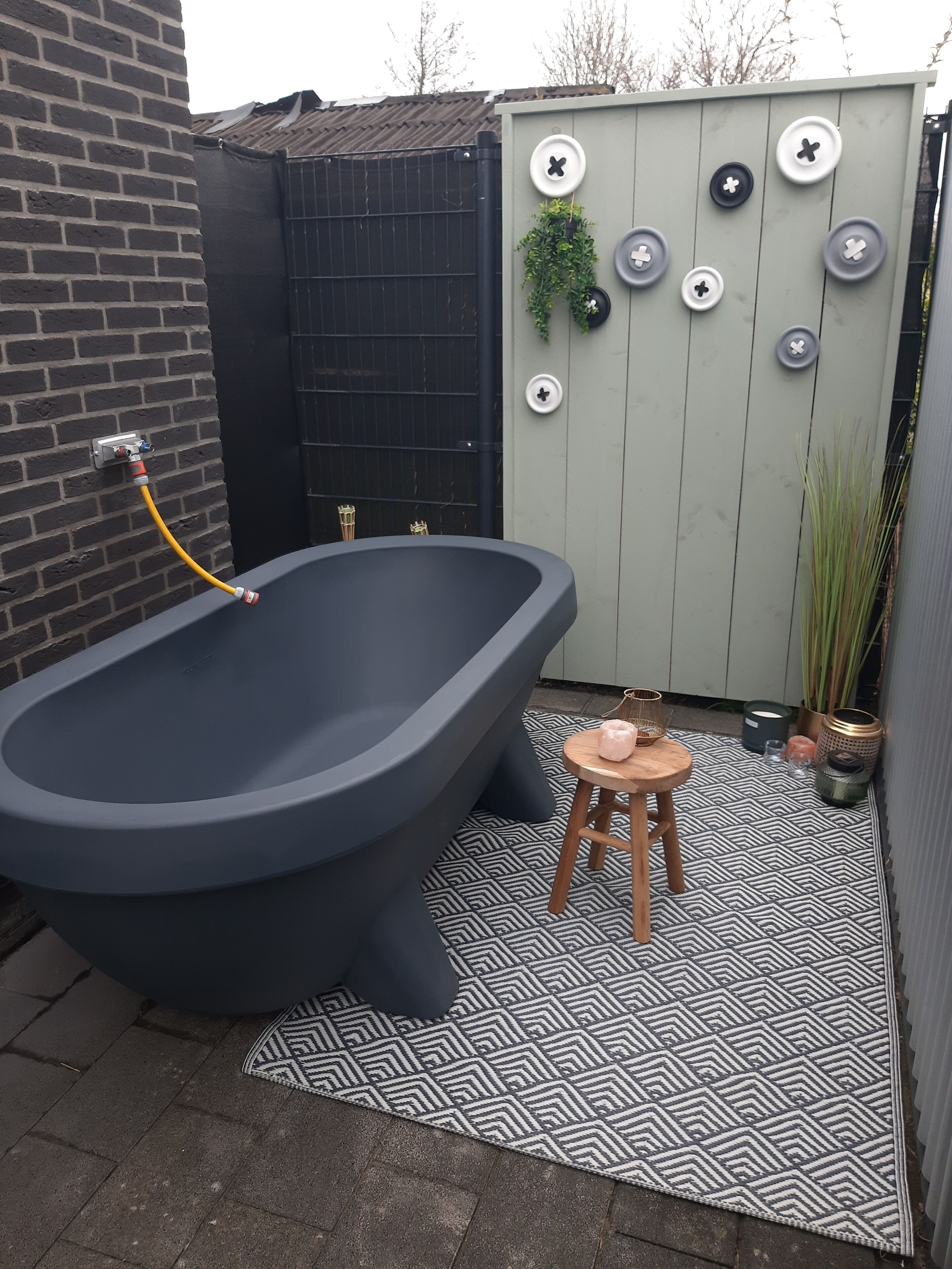 Un bagno esterno moderno con una vasca da bagno grande, uno sgabello piccolo e un tappeto decorato.