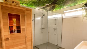 A bathroom with a wooden bath house, a glass-enclosed shower area, and a white sink.