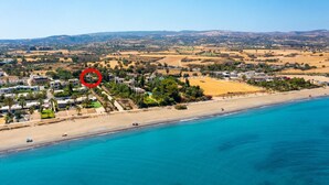 Luftaufnahme einer Küstenstadt mit Strand, Häusern und einem roten, markierten Bereich.