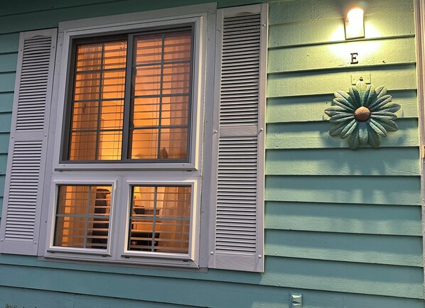 Une maison avec deux fenêtres, chacune dotée de volets, et un luminaire décoratif fixé au mur.