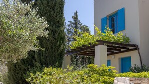 A building with blue shutters and a stone wall. - Villa Eleni (Hersonissos)