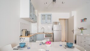 A modern kitchen with white cabinets, a built-in oven, and a dining area with a white table set for four.