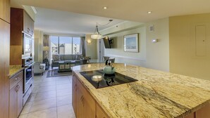A modern kitchen with a granite countertop, built-in oven, and a dining area with a sofa and chairs. - Sunset Rentals | Villamare 3520 (Hilton Head Island)