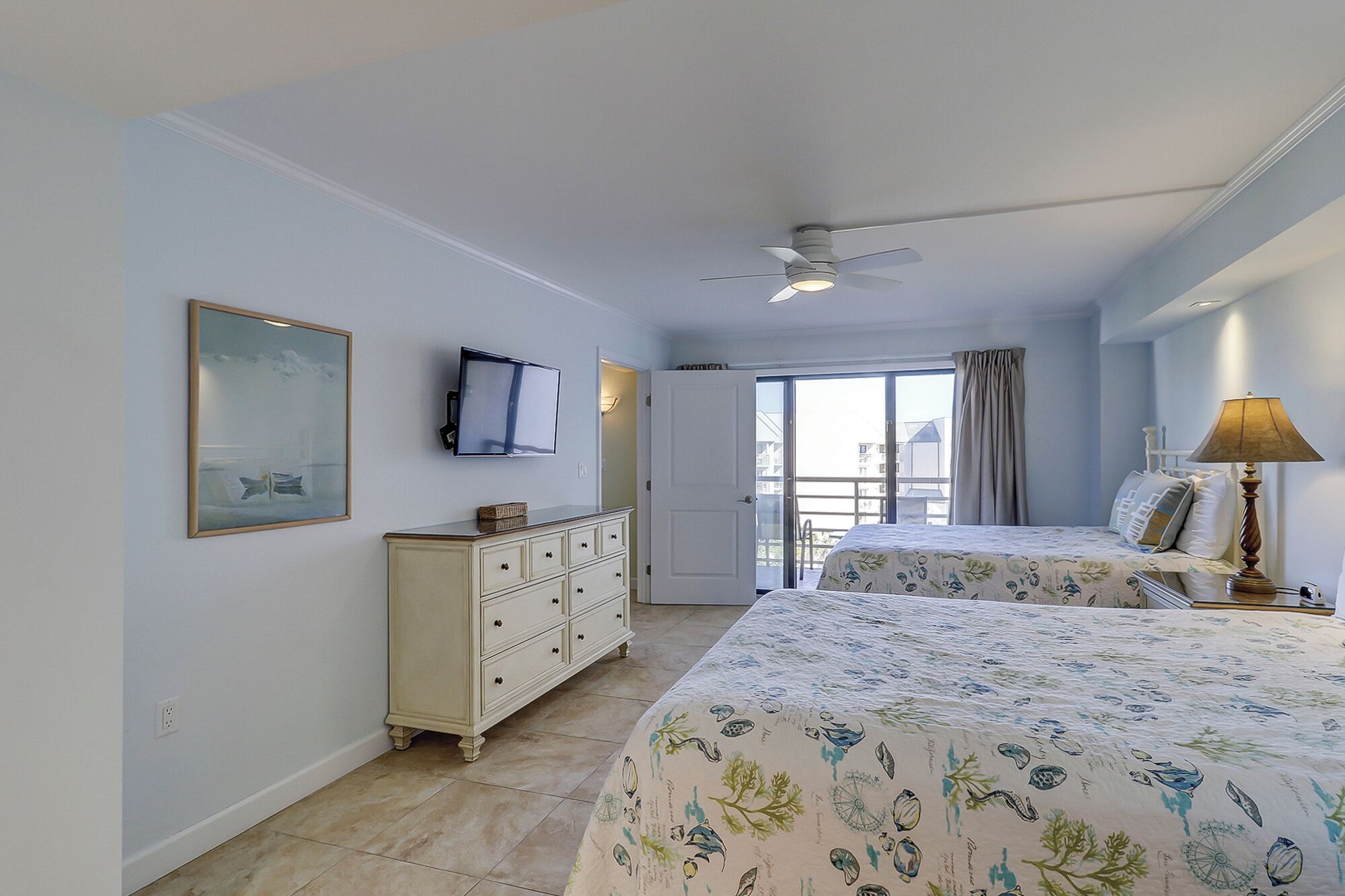 Un dormitorio con cama, cómoda, televisor y balcón.