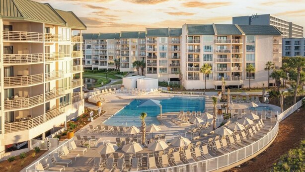 A hotel with multiple floors, a swimming pool, and outdoor seating areas. - Sunset Rentals | Villamare 3520 (Hilton Head Island)