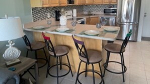 Une cuisine dotée de meubles en bois, d’un réfrigérateur en acier inoxydable et d’un îlot central avec des tabourets de bar.