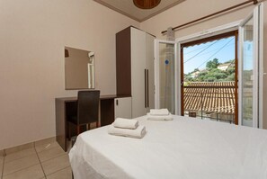 Ein Schlafzimmer mit Bett, Schreibtisch, Stuhl, Kleiderschrank und einer Badezimmertür.
