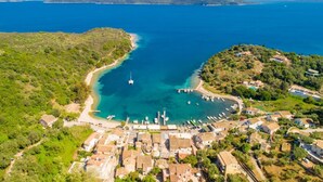 An aerial view of a coastal town with a marina, houses, and a clear blue sea. - Foteini Apartment - Two Bedroom Apartment, Sleeps 2 (Corfu)