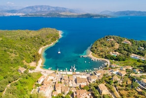An aerial view of a coastal town with a marina, houses, and a clear blue sea.