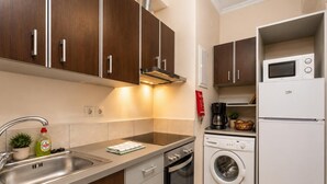 A compact kitchen with a sink, stove, oven, microwave, and a built-in washing machine. - Foteini Apartment - Two Bedroom Apartment, Sleeps 2 (Corfu)