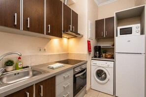 Uma cozinha compacta com pia, fogão, forno, micro-ondas e máquina de lavar embutida.
