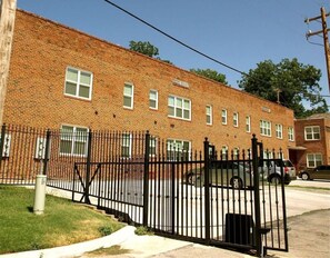 Stately building with a symmetrical facade and evenly spaced windows, featuring a central entrance and a secure parking area.