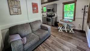 Cocina moderna con electrodomésticos de acero inoxidable, techo de madera y vista a la vegetación a través de una ventana.