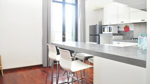 Eine moderne Küche mit weißen Schränken, einer grauen Arbeitsplatte und einem Fenster mit Vorhängen.