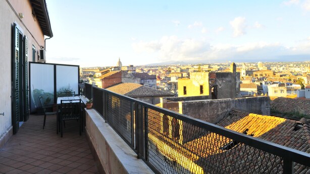 Ein Balkon mit Blick auf eine Stadtlandschaft, darunter Gebäude und eine Kuppel.