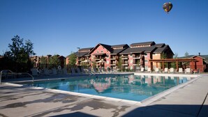 A hotel with a swimming pool, lounge chairs, and a hot air balloon in the sky. - Beautiful Steamboat Springs Resort (Steamboat Springs)