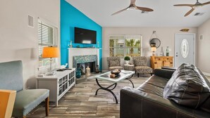 A living room with a fireplace, a sofa, a coffee table, and two ceiling fans.