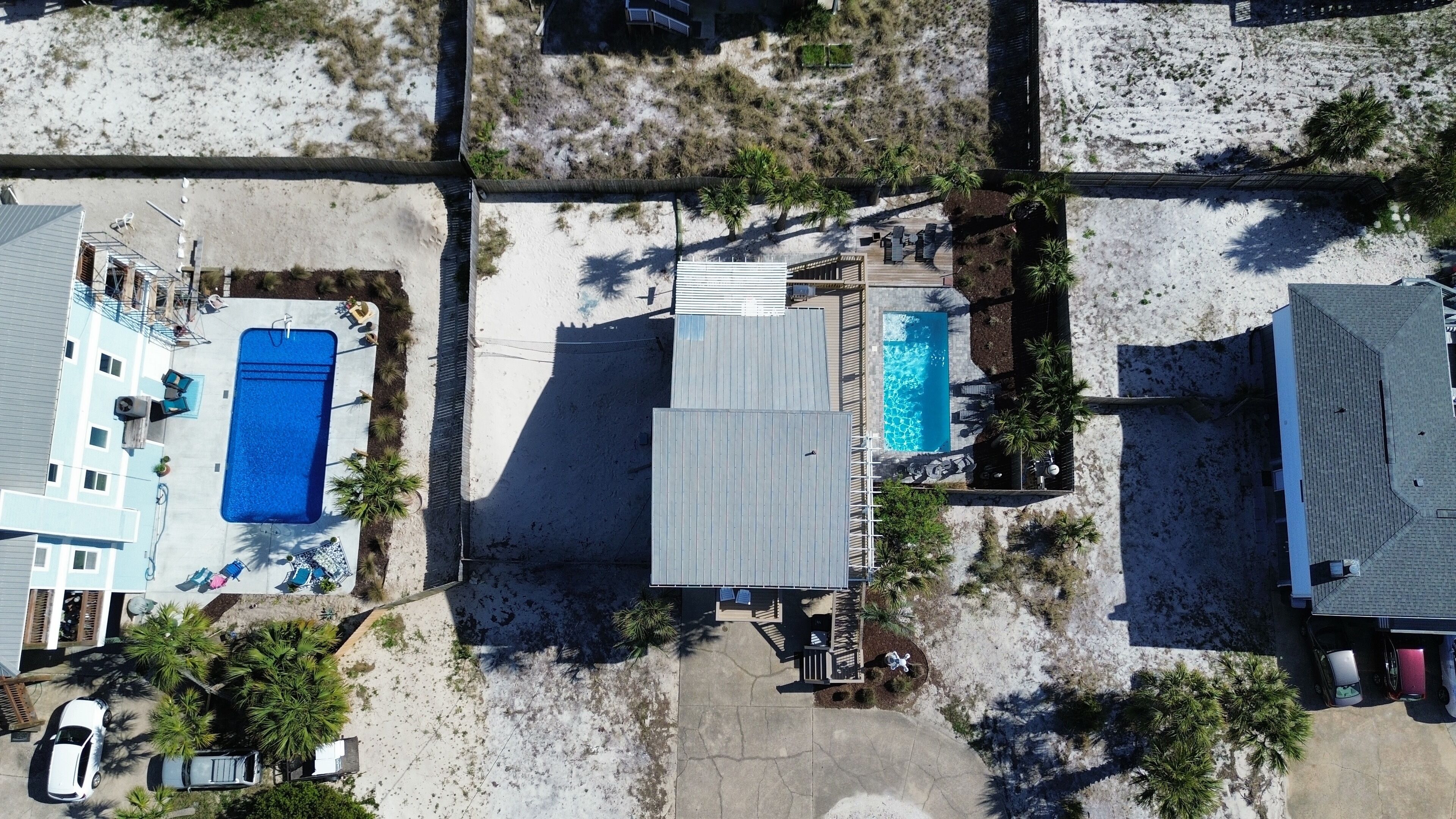 Vista aérea de una zona residencial con dos piscinas, un patio cubierto y un área de estacionamiento pequeña.