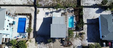 Vista aérea de una zona residencial con dos piscinas, un patio cubierto y un área de estacionamiento pequeña.
