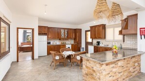 Una cocina moderna con armarios de madera, un comedor con sillas de mimbre y una isla grande con salpicadero de piedra.