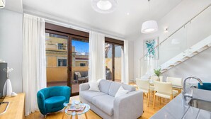 A modern living room with a sofa, a glass coffee table, and a dining area with chairs.