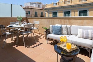 A terrace with a dining table, chairs, a sofa, and a small table with drinks. - Maroma - Holiday Penthouse Malaga City (Málaga)