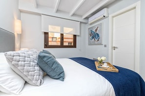 A bedroom with a bed, a window, a door, and a wall-mounted air conditioner. - Maroma - Holiday Penthouse Malaga City (Málaga)
