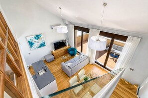 Una sala de estar moderna con sofá, televisión y comedor con mesa de vidrio.