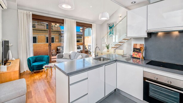 A modern kitchen with a central island, stainless steel appliances, and a view to an outdoor balcony.