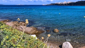 A coastal landscape with clear blue water, rocky shoreline, and distant mountains. - Maison Monte d'A Rena (La Maddalena)