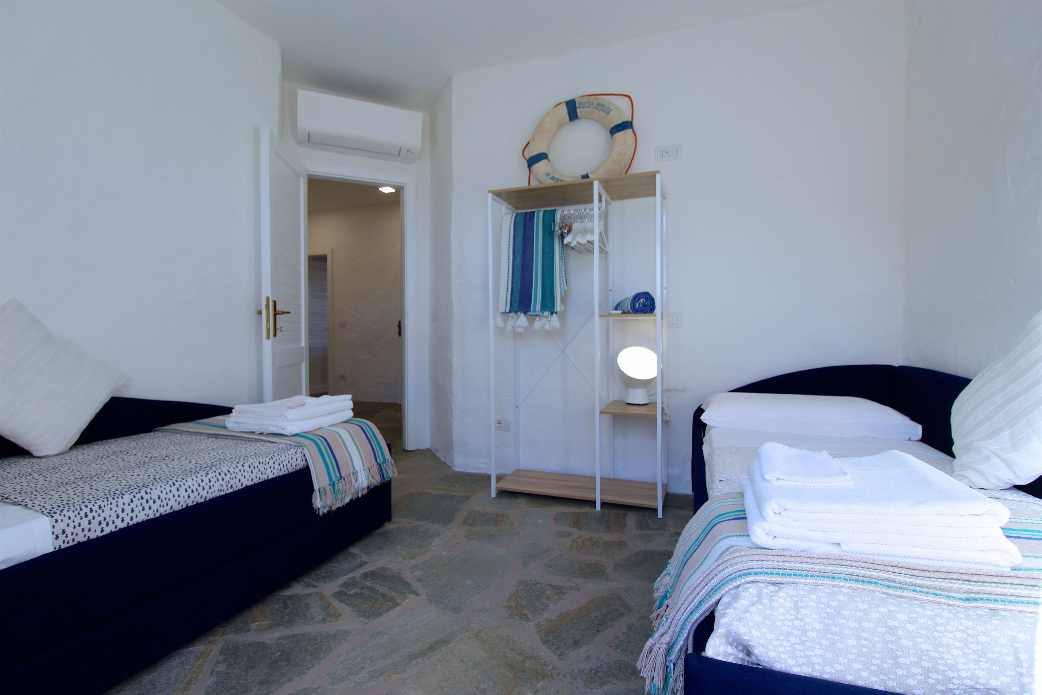 Une chambre avec deux lits, une armoire et un gilet de sauvetage accroché au mur.
