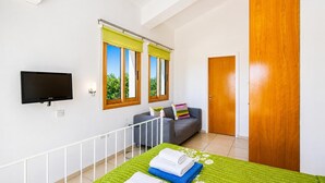 A bedroom with a bed, a TV, a sofa, and a door. - Argaka Sunset Villa - Three Bedroom Villa, Sleeps 6 (Argaka)