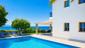 A swimming pool with lounge chairs, a covered patio, and a view of the sea. - Argaka Sunset Villa - Three Bedroom Villa, Sleeps 6 (Argaka)